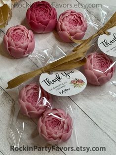 some pink flowers are in plastic bags on a white wooden table and there is a tag that says thank you