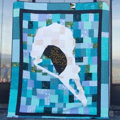 a blue and white quilt with a silhouette of a woman holding an umbrella on it