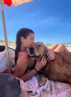 a woman laying on top of a bed next to a brown and white dog under an umbrella