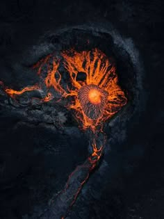 an aerial view of lava and fire in the ocean, with bright orange flames coming from it