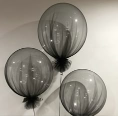 three clear balloons are hanging on the wall