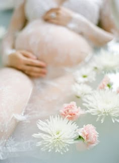 a pregnant woman sitting in a bathtub with flowers