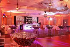 a room filled with tables and chairs covered in white tablecloths next to balloons