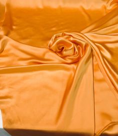 an orange cloth is laying on top of a white surface with the fabric pulled back