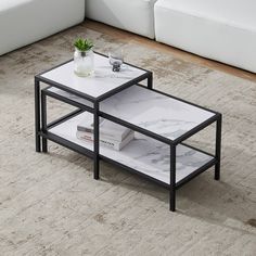 two tables sitting on top of a carpeted floor next to a white couch in a living room