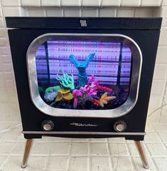 an old fashioned television with a fake animal on it's display stand in front of a brick wall