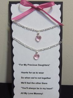 a card with two hearts attached to it and a pink ribbon tied around the neck