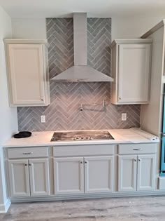 an empty kitchen with white cabinets and gray tile backsplashes on the wall