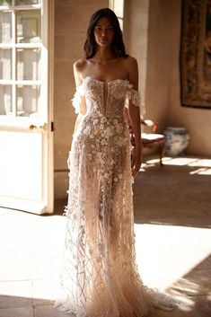 a woman standing in a room wearing a dress with flowers on the front and side