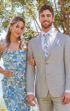 a man in a suit and tie standing next to a woman wearing a floral dress