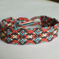 a close up of a bracelet on a white surface with blue, red and black beads