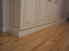 a kitchen with white cabinets and wood floors