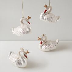 three white swan ornaments hanging from strings