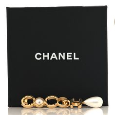 This is an authentic CHANEL Pearl Coco CC Brooch in Gold. This light gold brooch features Chanel CC logos and a stylized "COCO" name embellished with resin pearls and a CC logo dangle. Coco Name, Cc Brooch, Chanel Pearl, Chanel Pearls, Gold Chanel, Gold Brooch, Gold Brooches, Cc Logo, Coco