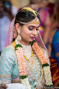 a woman in a bridal outfit with flowers on her head and necklaces around her neck