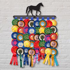 a wall hanging made out of ribbons and bottle caps with a horse on the top