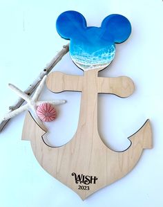 a wooden cutout of an anchor with a mouse on it and seashells