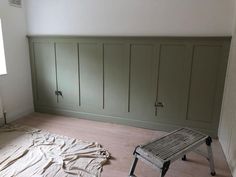 an empty room with green paneling on the walls and a wooden bench in the middle