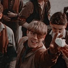 a group of young men standing next to each other holding food in one hand and looking at the camera