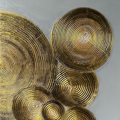 three gold plates sitting next to each other on a white tablecloth covered surface with circles in the middle