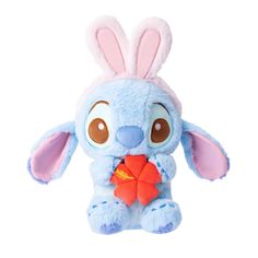 a blue stuffed animal with brown eyes and ears holding a red object in it's mouth