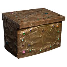 an ornate metal box with colorful glass beads on the lid and sides, sitting against a white background