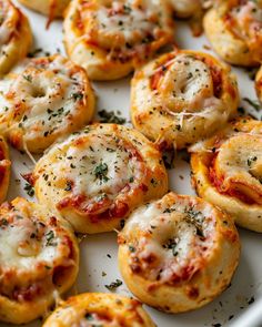 mini pizzas with cheese and sauce on a white platter ready to be eaten