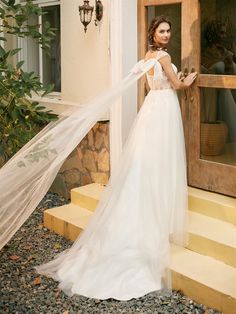 a woman in a wedding dress is standing on the steps with her veil over her head