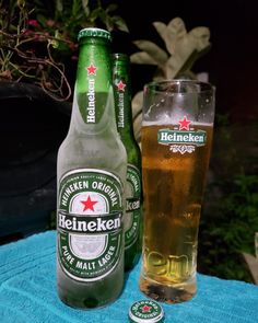 a bottle and glass sitting on a towel next to each other, with one empty beer in the foreground