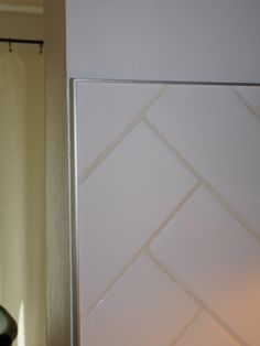 the corner of a bathroom with a white tile wall