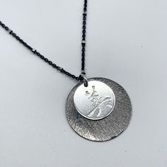 "This layered disc pendant is featured in Oxidized silver and Bright sterling silver, and it is hand stamped with a Chinese Character for \"Beautiful\". The outer circle is approximately 20mm and the inner circle is 11mm in diameter. The pendant has a simple jump ring bail to let it slide on the Oxidized chain with bright sterling silver dots.  The size is perfect for someone who just wants a simple everyday necklace. Please choose your chain length preference, 16\", 18\" or 20\".  This pieces i Silver Coin Necklace With Oxidized Round Pendant, Sterling Silver Charm Necklace With Oxidized Round Pendant, Symbolic Oxidized Round Pendant Necklace, Oxidized Silver Circular Jewelry, Oxidized Sterling Silver Round Disc Jewelry, Sparkle Earrings, Disc Pendant, Everyday Necklace, Oxidized Silver