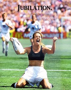 a woman sitting on the ground with her arms in the air as she is celebrating