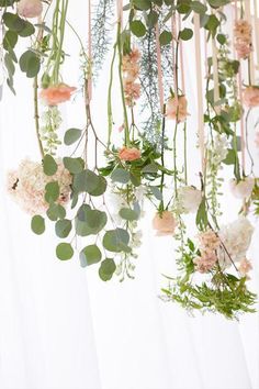 flowers and greenery hanging from the ceiling in front of a white backdrop with curtains