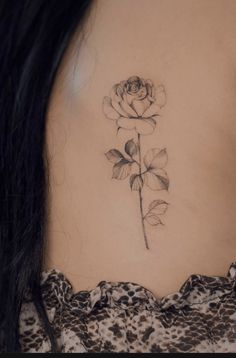 a woman's back with a rose tattoo on her left side ribcage