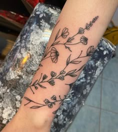 a woman's arm with flowers and leaves tattooed on the left side of her arm