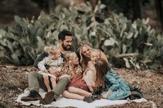 a family sitting on a blanket in front of cacti