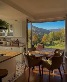 a kitchen with a table and chairs in front of a window that looks out onto the mountains