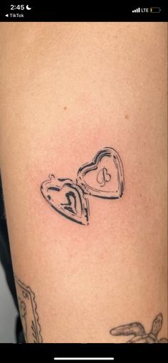 a woman's thigh with a heart and two lockes tattoo on her leg