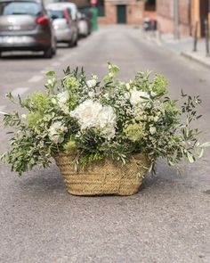 a basket filled with white flowers sitting on the side of a road