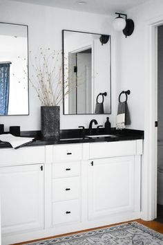 a bathroom with two sinks, mirrors and a rug in front of the sink area