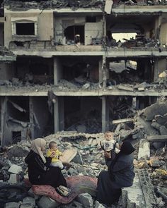 two women and a baby are sitting in the rubble