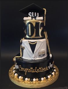 a graduation cake is decorated with black and gold