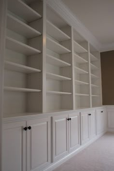 empty white bookcases in the corner of a room with carpeted flooring