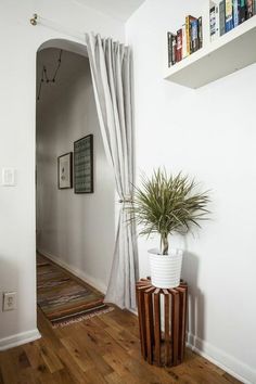 a potted plant sitting on top of a wooden table next to a window with white drapes