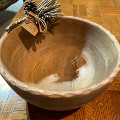 a wooden bowl on a table with several silverware in it and a tag hanging from the top