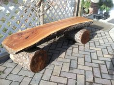 a wooden bench sitting on top of a brick patio next to a fence and tree