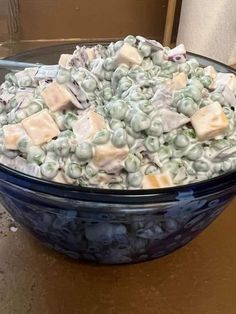 a blue bowl filled with lots of food on top of a wooden table next to a wall