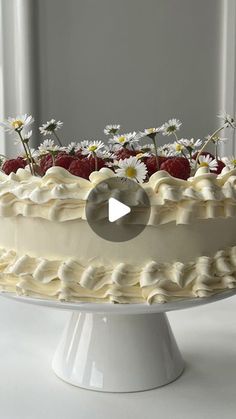 a white cake with strawberries and daisies on top