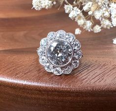 a diamond ring sitting on top of a wooden table next to some white flower petals