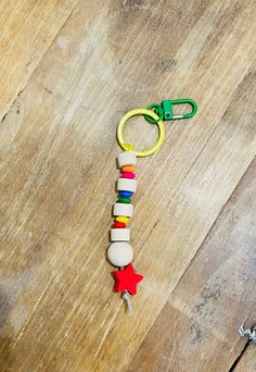 a wooden keychain with beads and stars on it sitting on a wood floor